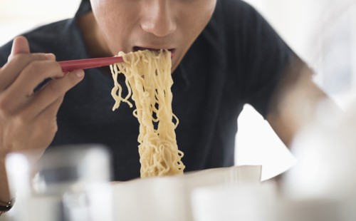 Man eating noodles with chopsticks.