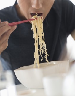 Man eating noodles with chopsticks.