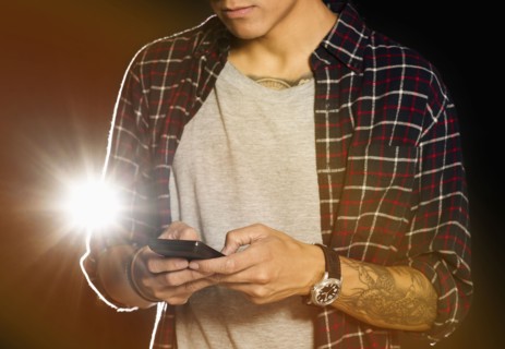 Mid section of man text messaging at night.