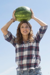 Young woman carrying on head watermelon.