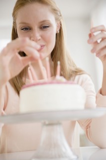 Woman putting candles on birthday cake