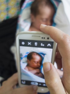 Mother photographing newborn daughter