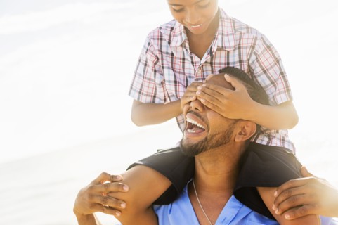 Father and son (10-11) having fun on beach