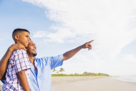 Father and son (10-11) embracing on beach