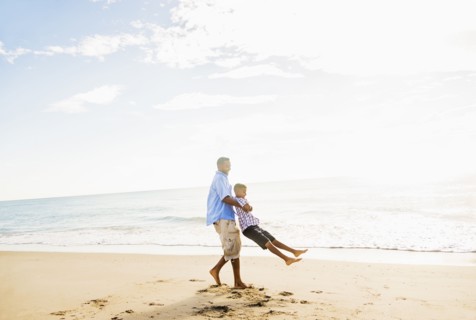 Father and son (10-11) having fun on beach