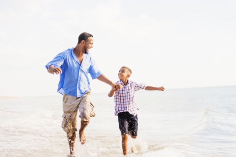 Father and son (10-11) running on beach