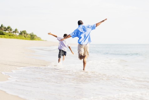 Father and son (10-11) running on beach