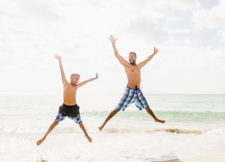 Father and son (10-11) having fun on beach