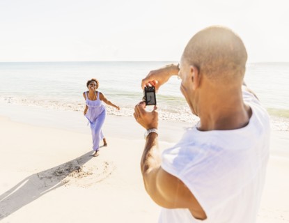 Man photographing woman on beach