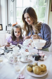 Mother and daughter (4-5) eating together in dining room