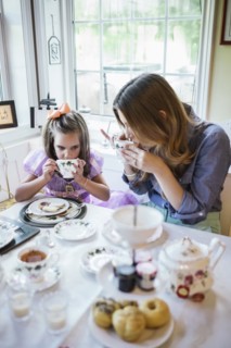 Mother and daughter (4-5) eating together in dining room