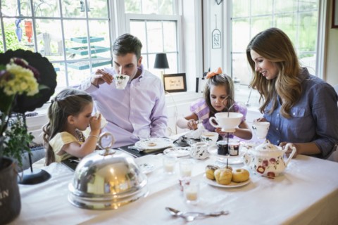 Parents and daughter (4-5) eating together in dining room