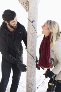 Young couple decorating house with christmas lights