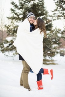 Couple wrapped in blanket standing in snow