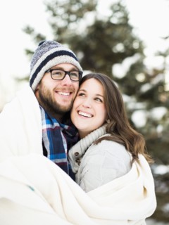 Portrait of couple wrapped in blanket smiling outdoors