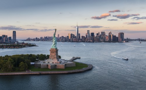 Aerial view of city with Statue of Liberty at sunset. New York City, New York.