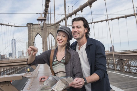 Happy couple with map on Brooklyn Bridge. Brooklyn, New York.