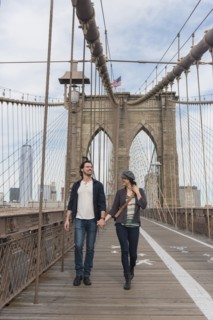 Couple holding hands and walking on Brooklyn Bridge. Brooklyn, New York.