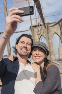 Happy couple taking selfie on Brooklyn Bridge. Brooklyn, New York.