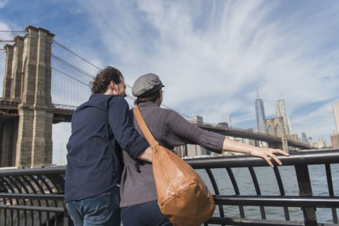 Couple leaning against railing and looking at Freedom Tower. Brooklyn, New York.