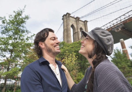 Happy couple standing against Brooklyn Bridge. Brooklyn, New York.