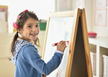 Portrait of girl (6-7) writing on board in classroom.