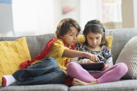 Children (6-7) playing game on tablet pc at home.