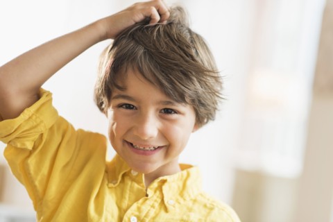 Portrait of smiling boy (6-7) with hand in hair.