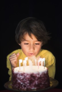 Portrait of boy (6-7) blowing out birthday candles.