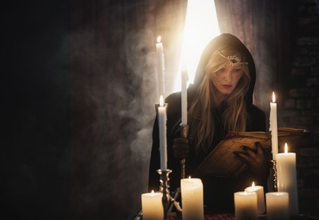 Sorceress reading book in dark room.
