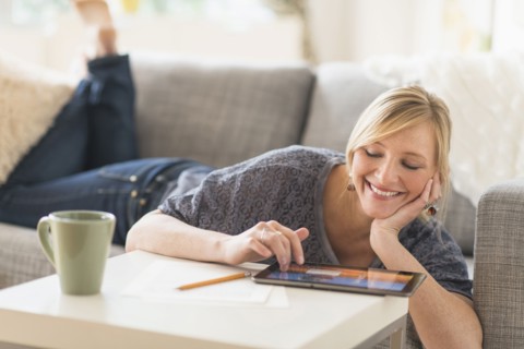 Woman lying down on sofa with tablet pc.