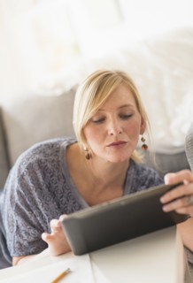 Woman lying down on sofa with tablet pc.