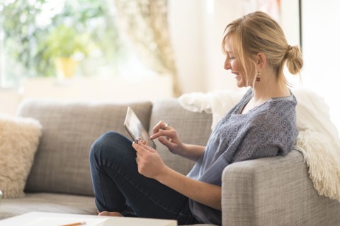 Woman sitting on sofa and using tablet pc.