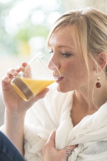 Woman sitting in living room and drinking orange juice.
