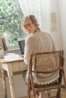 Smiling woman sitting at desk and looking over shoulder.