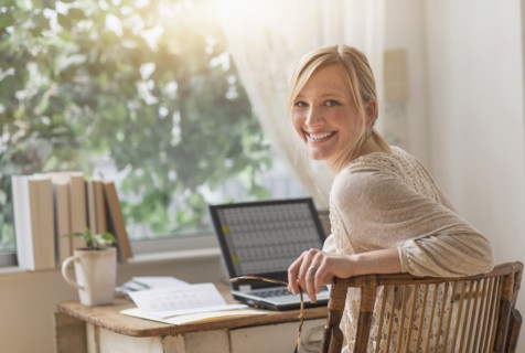 Smiling woman sitting at desk and looking over shoulder.
