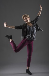 Studio shot of cheerful woman with arms raised.