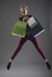 Studio shot of woman jumping with shopping bags.