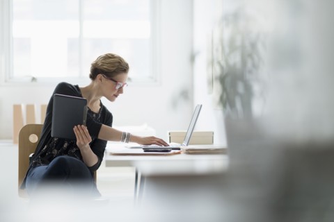 Businesswoman using laptop in office.