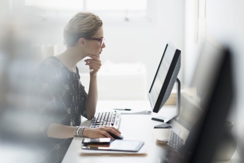 Side view of business woman working on desktop pc in office.