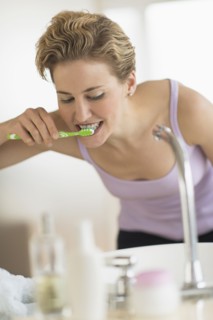 Young woman brushing teeth in bathroom.
