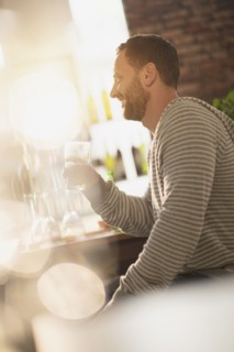 Side view of man having drink in bar.