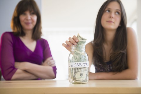 Teenage girl (14-15) putting money in swear jar