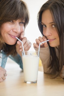 Teenage girl (14-15) drinking milk with her mom at home