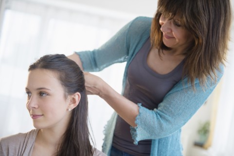 Mom tying up daughter's (14-15) hair