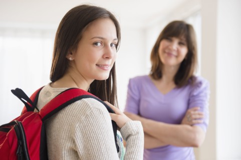 Portrait of teenage student (14-15), mother in background