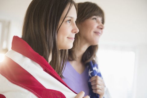 Teenage girl (14-15) and her mom wrapped in American Flag on Fourth of July