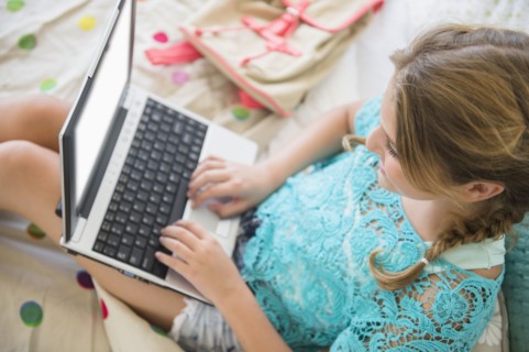 Girl (12-13) using laptop in bedroom