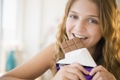 Girl (12-13) eating chocolate