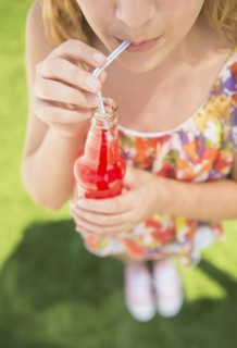 Girl (12-13) drinking soda from bottle using straw
